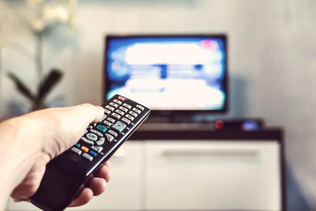Person pointing remote at tv